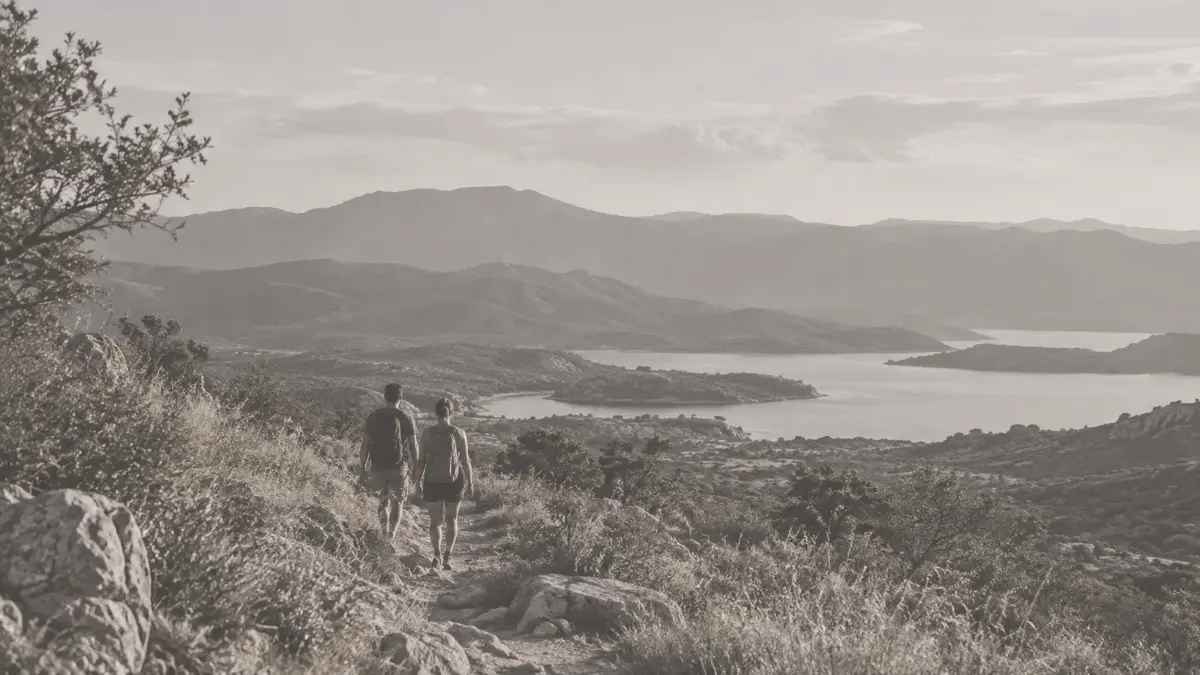 Dos personas caminando por un sendero serrano hacia el valle